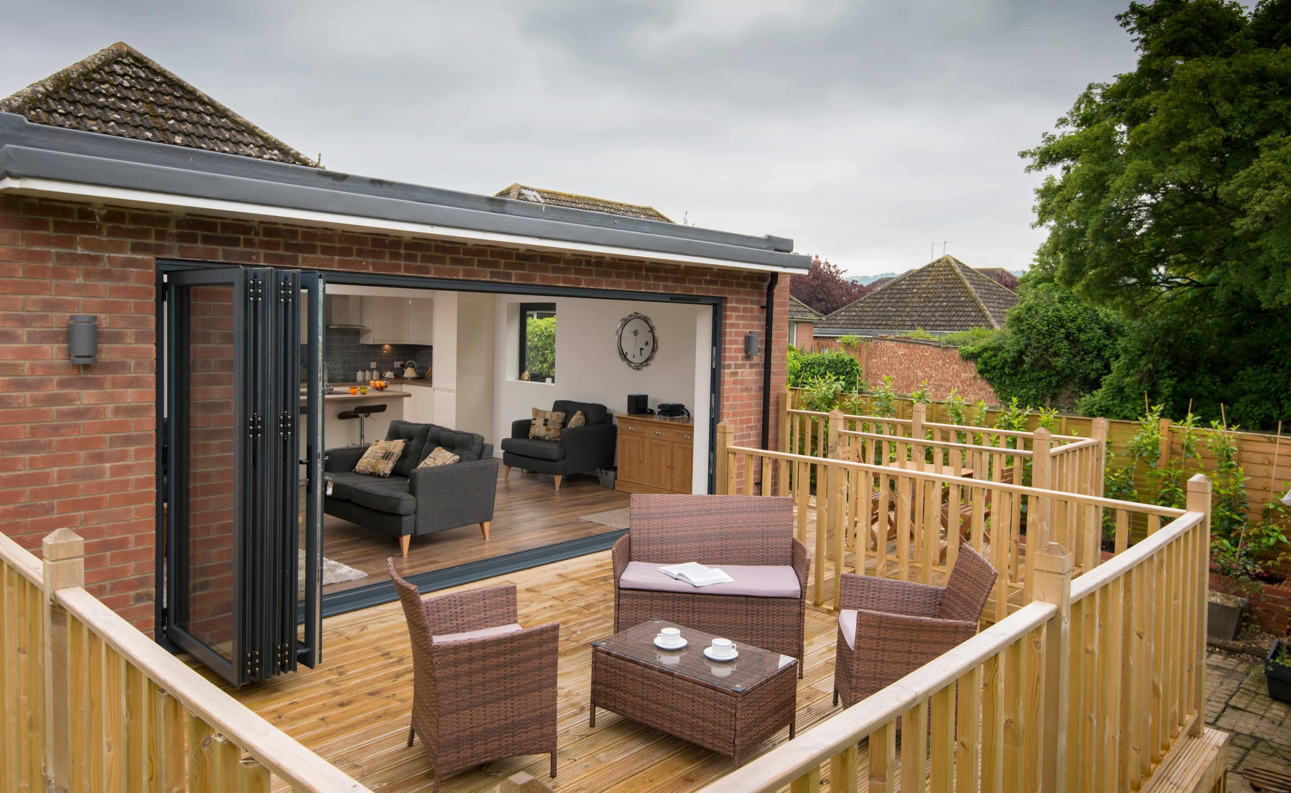origin bifold doors leading out to decking with rattan chairs